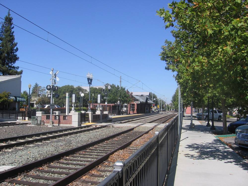 The light rail platform at Downtown Campbell station, with the brick station building and tracks running past shopfronts.